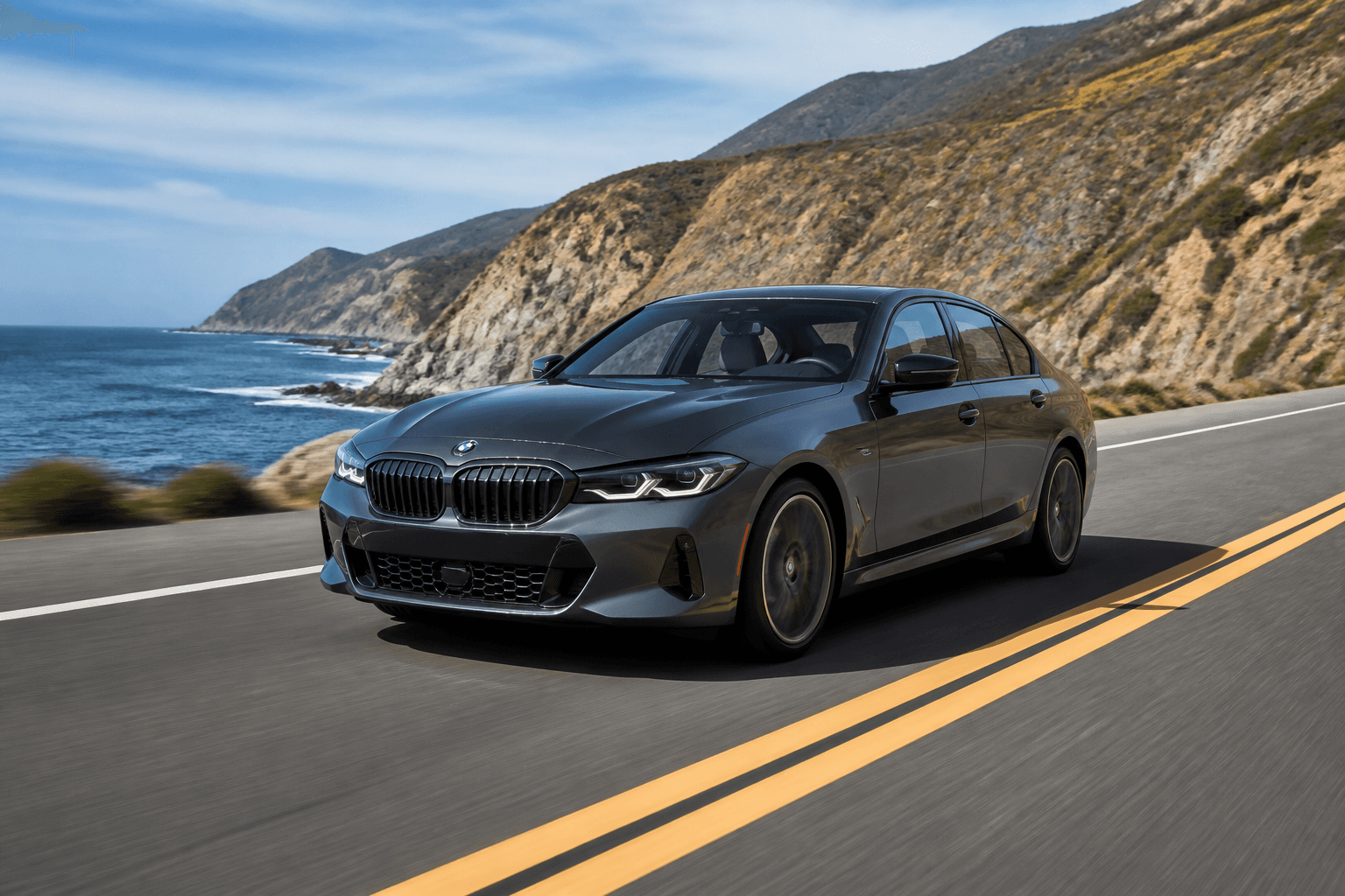 Gunmetal grey BMW sedan cruising a coastal highway